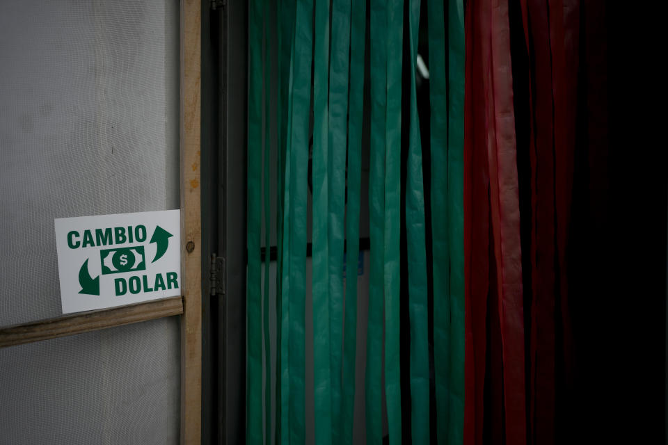 A money exchange sign hangs outside a shop along the road connecting Gualeguaychu in the province of Entre Rios, Argentina, with the Uruguayan border, Friday, June 30, 2023. Uruguayans are crossing the border to Argentina for shopping bargains created by different exchange rates in the South American countries as crisis-battered Argentina’s peso has plunged against the U.S. dollar and its annual inflation tops 100%, one of the highest rates in the world. (AP Photo/Natacha Pisarenko)