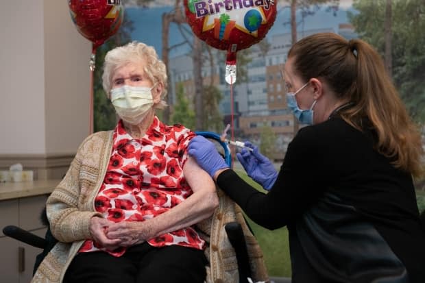 Phyllis Ridgway, left, receives a COVID-19 vaccination on Saturday at Toronto's Sunnybrook Health Sciences Centre. At age 114, she is the oldest known living person in Canada. (Kevin Van Paassen/Sunnybrook Health Sciences Centre - image credit)