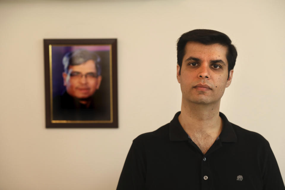 Karan Murgai, an IT management consultant for a multinational based in Dallas, poses for a photograph next to then portrait of his father Satish Murgai, in his Delhi house, in New Delhi, India, Tuesday, June 30, 2020. Murgai came to Delhi in March this year after his father died. Murgai and at least 1,000 others like him, whose U.S. visas are tied to their jobs in the U.S., are now stranded in India, after an executive order signed by President Donald Trump that suspends applications for H-1B and other high-skilled work visas from abroad. (AP Photo/Manish Swarup)