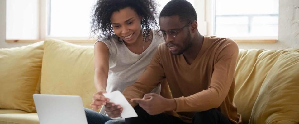 Happy young african american couple using calculator and laptop for calculating finance rates.