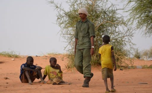 A group of Mali army deserters walks past children in a camp near Niamey on May 25. Mali's embattled transitional government has rejected a rebel alliance's declaration of an Islamic state in the vast desert north, a move that has plunged the nation closer to breakup two months after a coup