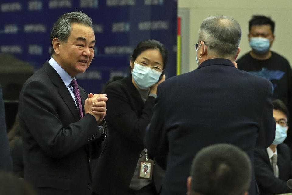 Chinese Foreign Minister Wang Yi, left, is greeted by attendees as he arrives the Lanting Forum on bringing China-U.S. relations back to the right track, at the Ministry of Foreign Affairs office in Beijing on Monday, Feb. 22, 2021. Wang called on the U.S. Monday to lift restrictions on trade and people-to-people contacts while ceasing what Beijing considers unwarranted interference in the areas of Taiwan, Hong Kong, Xinjiang and Tibet. (AP Photo/Andy Wong)