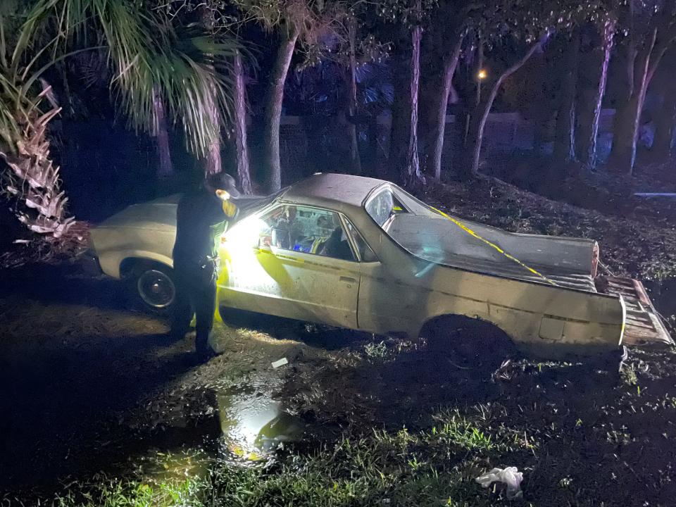 A sheriff's deputy puts yellow crime scene tape around a Chevy El Camino that's in the ditch along County Road 315 early Saturday. FHP troopers believe a pedestrian who was hit and killed on the roadway previously had been driving this vehicle.
