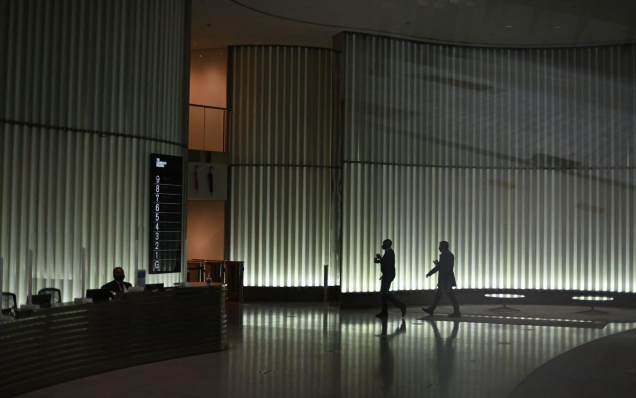 Two people walk through the almost deserted foyer of an office building in the City of London last week - Daniel Leal-Olivas/AFP