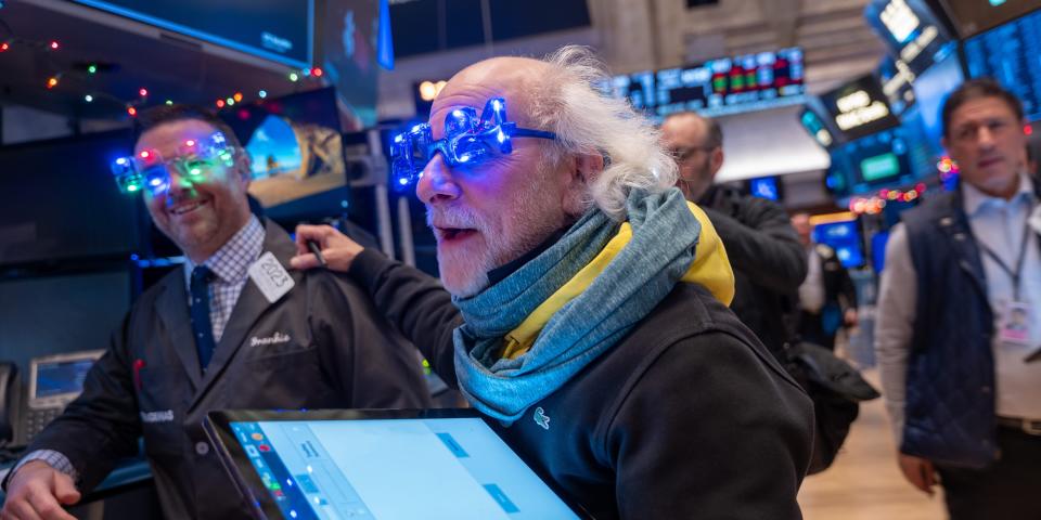 Traders work on the floor of the New York Stock Exchange wear light up glasses with the year 2024 on them
