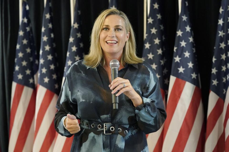 Senate candidate Tiffany Smiley speaks into a microphone in front of a backdrop of American flags.