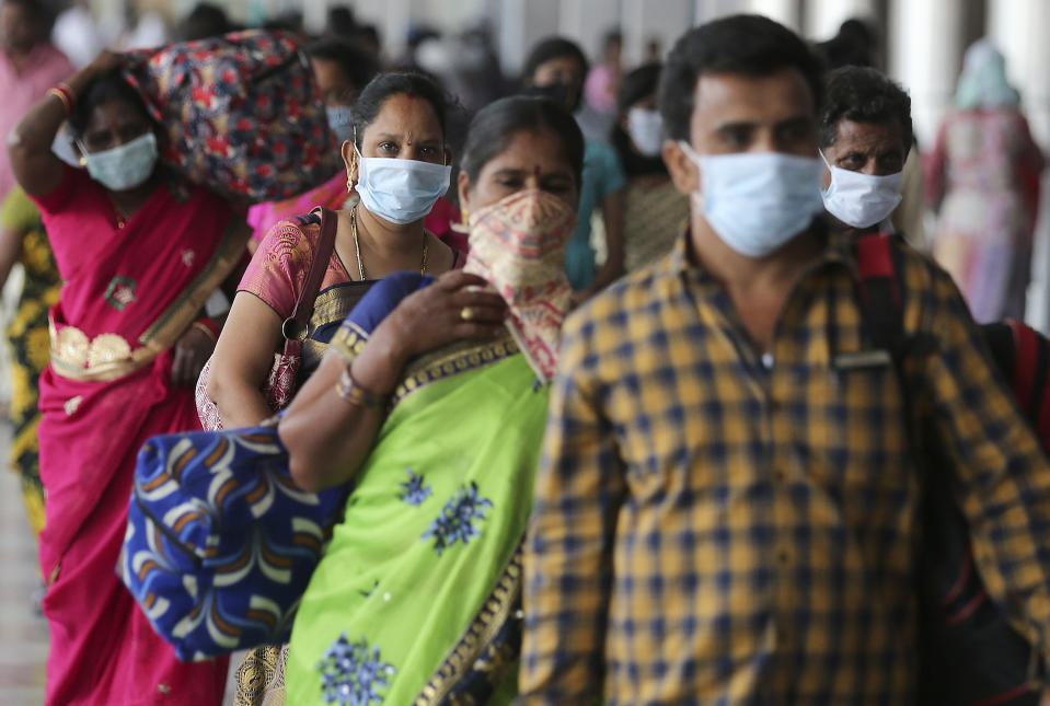 Indian passengers wear face masks as a precaution against COVID-19 arrive at Secunderabad Railway Station in Hyderabad, India, Saturday, March 21, 2020. For most people, the new coronavirus causes only mild or moderate symptoms. For some it can cause more severe illness. (AP Photo/Mahesh Kumar A.)