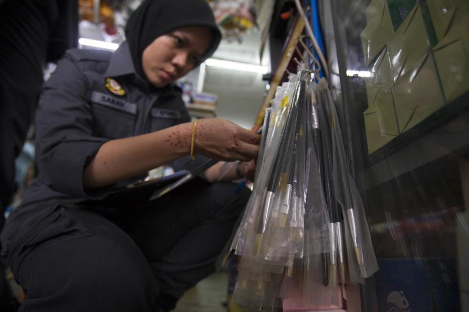 A domestic trade enforcement officer checks on the paint brushes that are believed to be made from pig bristles at a hardware store outside Kuala Lumpur, Malaysia on Wednesday, Feb. 8, 2017. Malaysian authorities have seized more than 2,000 paint brushes suspected to be made from pig bristles and sold without labels, in a crackdown following complaints from Muslim consumers. (AP Photo/Daniel Chan)