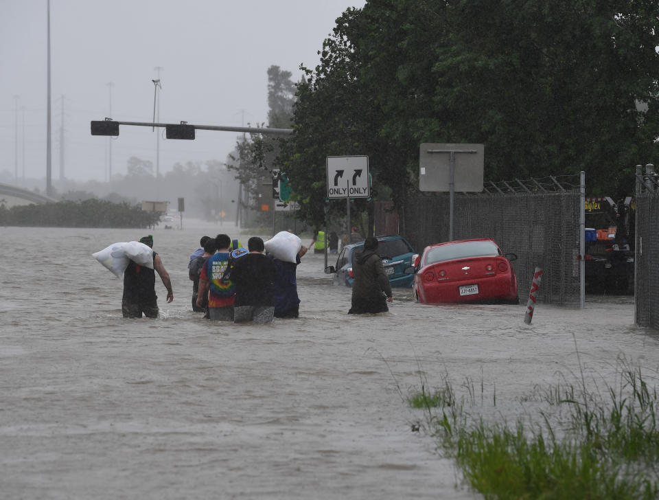 People walk through water to escape from their homes on Highway 90 after Hurricane Harvey caused heavy flooding in Houston, Texas on Aug. 28, 2017. (Photo: MARK RALSTON via Getty Images)