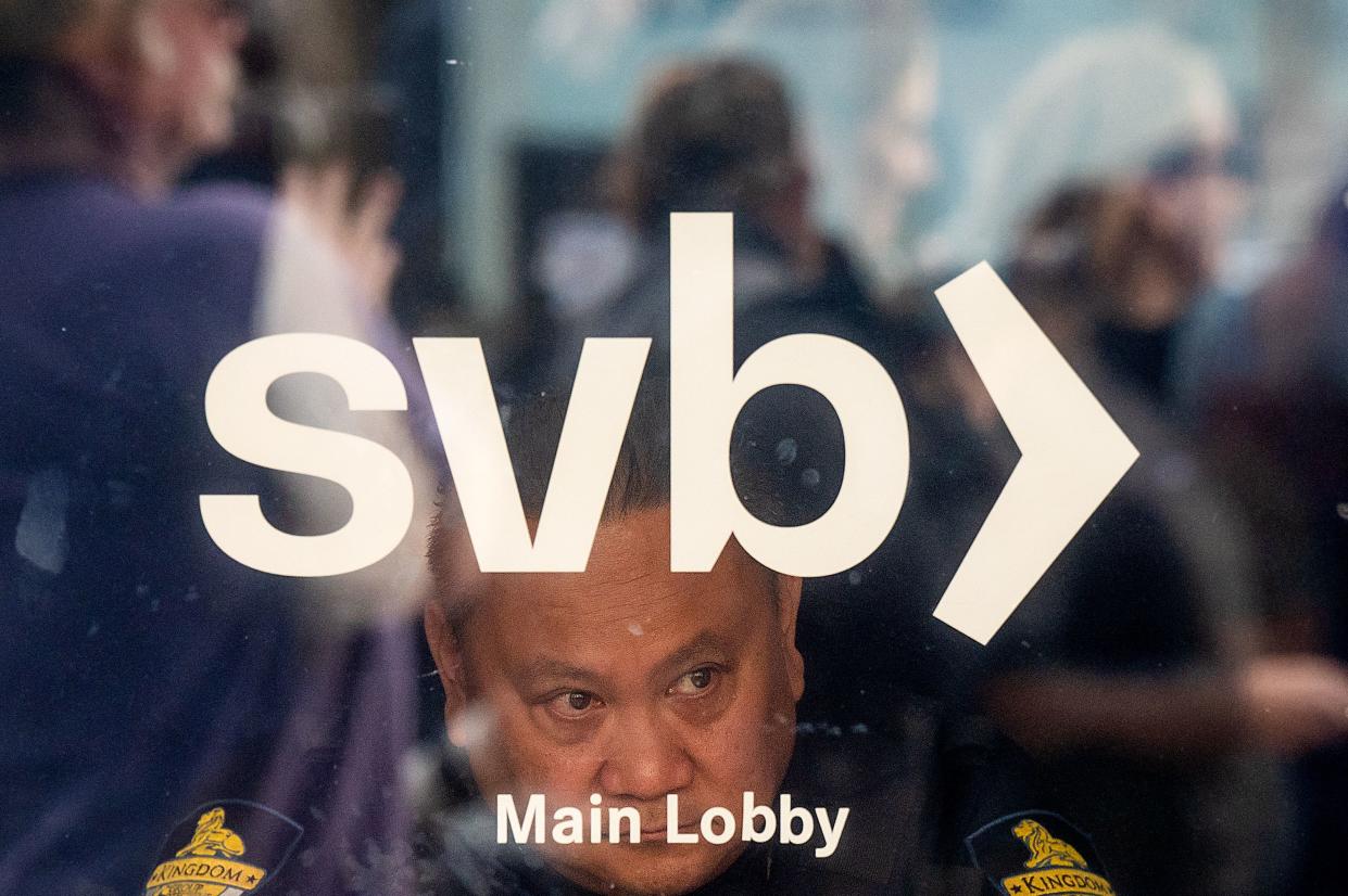 A security guard looks out a door as customers line up at Silicon Valley Bank headquarters