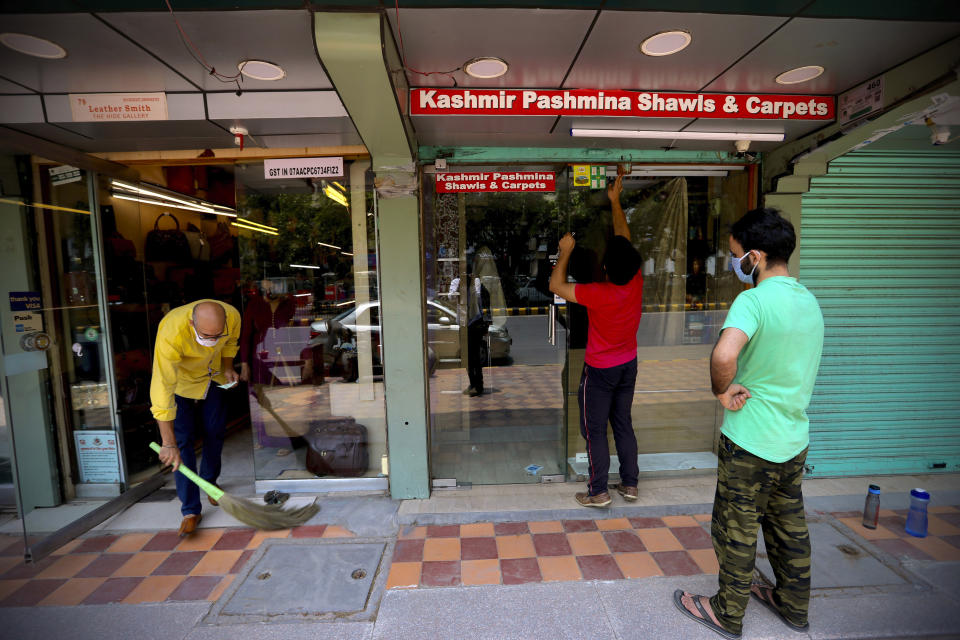 A man sweeps as people open their shops at the Janpath market in New Delhi, India, Monday, June 1, 2020. More states opened up and crowds of commuters trickled onto the roads in many of India's cities on Monday as a three-phase plan to lift the nationwide coronavirus lockdown started despite an upward trend in new infections. (AP Photo/Manish Swarup)