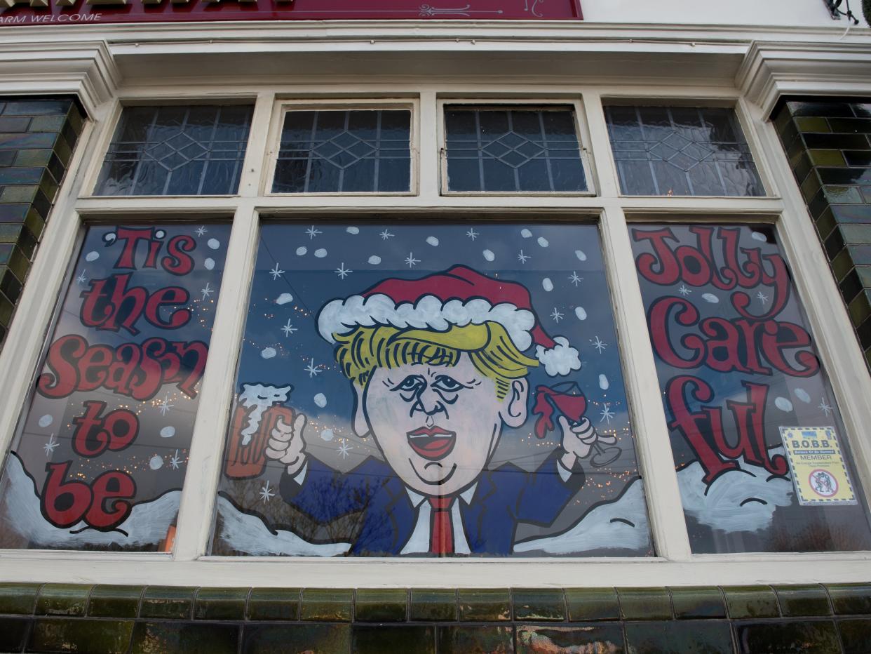 <p>A humorous decorated window on The Railway pub showing a caricature of Boris Johnson and the words ‘Tis the season to be jolly careful’</p> (Getty)