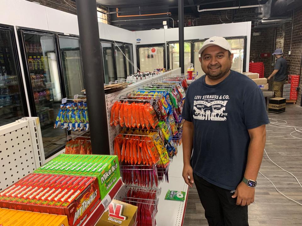 Keyur Patel, co-owner of the forthcoming Ian's Market in the 100 block of Gay Street, poses for a portrait as workers prepare the space for opening day. The convenience store, which would be adjoined by a fast-casual Indian restaurant, will have snacks, beer, lottery tickets and an ATM.