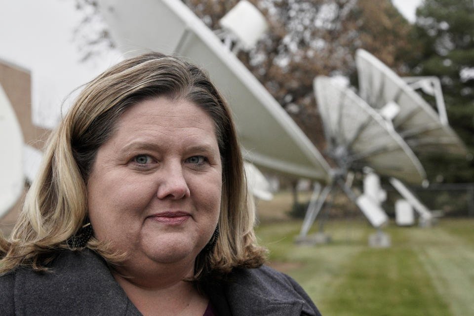 In this Nov. 21, 2019 photo, Shannon Booth, vice president and general manager for Gray Television who oversees company-owned Nebraska stations in Lincoln, Hastings and North Platte, poses for a photo in front of the KOLN television station's satellite dishes in Lincoln, Neb. An estimated 500,000 households nationwide don't have access to local broadcast channels because of a complicated federal law and a decades-long dispute between local broadcasters and satellite television providers. Households in the nation's "neglected markets" _ rural areas that can't get local broadcast signals, are forced to rely on satellite service with news from other states. (AP Photo/Nati Harnik)