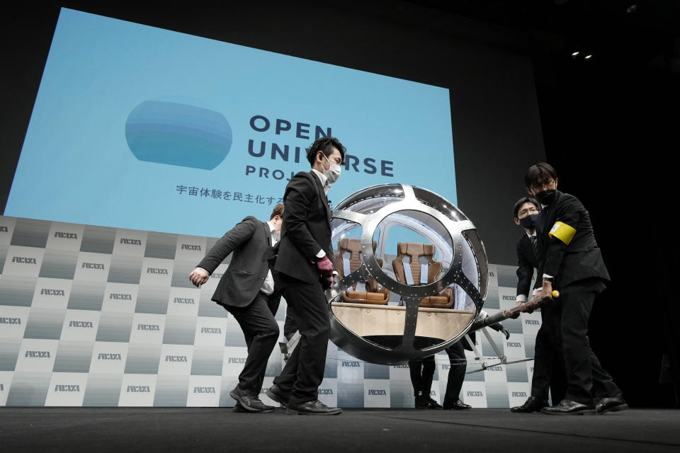 Staffers carry a two-seater cabin that a startup company says is capable of rising to an altitude of 15 miles, which is roughly the middle of the stratosphere, during a news conference in Tokyo, Tuesday, Feb. 21, 2023. The Japanese startup company announced plans Tuesday to launch a commercial space viewing balloon flight that it hopes will bring down to earth an otherwise astronomically expensive experience. (AP Photo/Eugene Hoshiko)