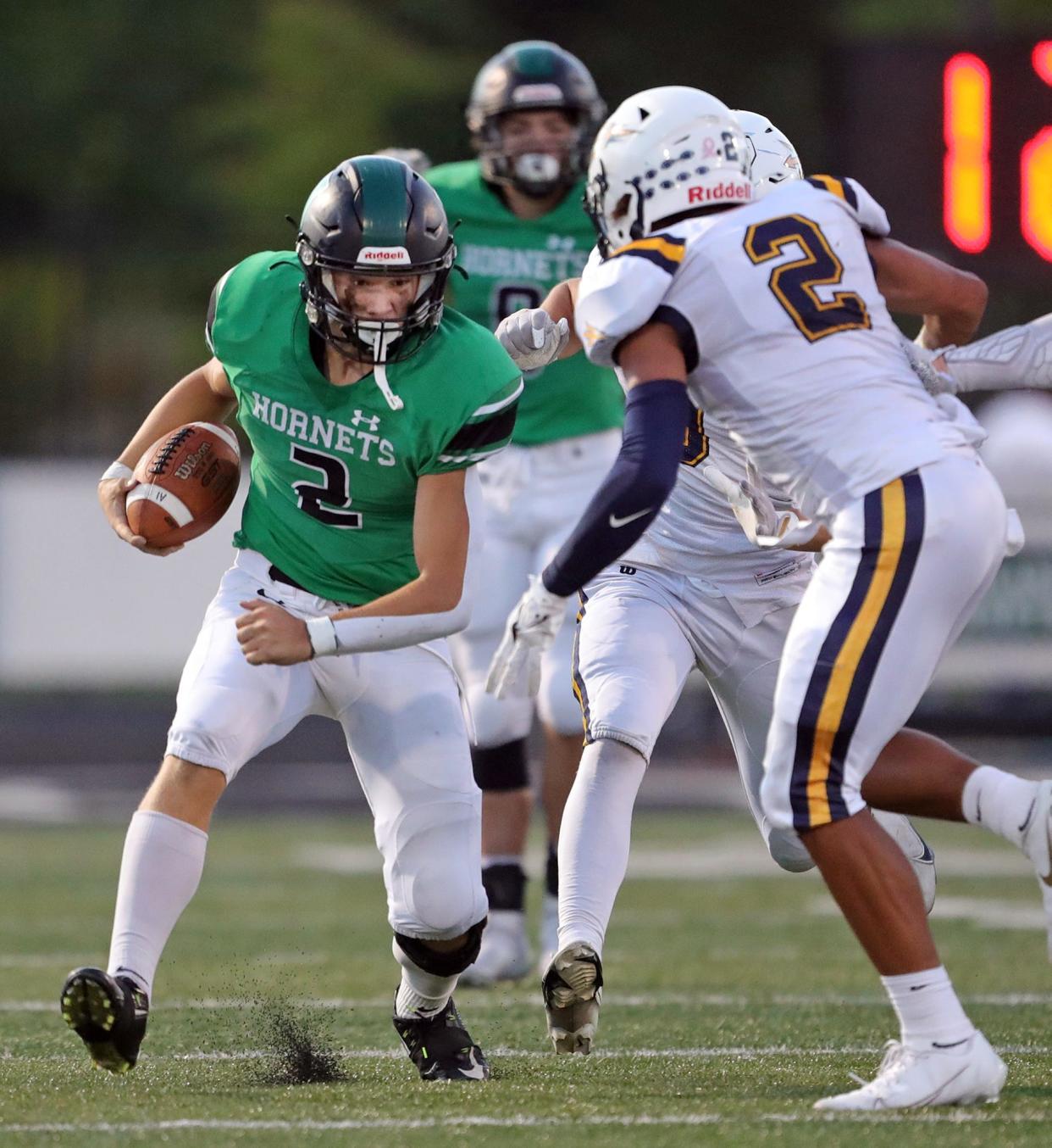 Highland quarterback Aaron Filips, left, rushes past Tallmadge linebacker Collin Dixon during the first half of a football game at Highland High School, Tuesday, Sept. 7, 2021, in Medina, Ohio.