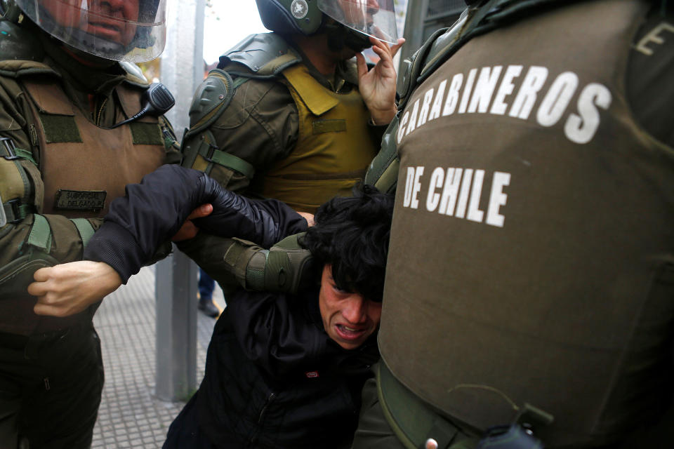 A demonstrator is detained during an unauthorized march called by secondary students to protest against government education reforms in Santiago