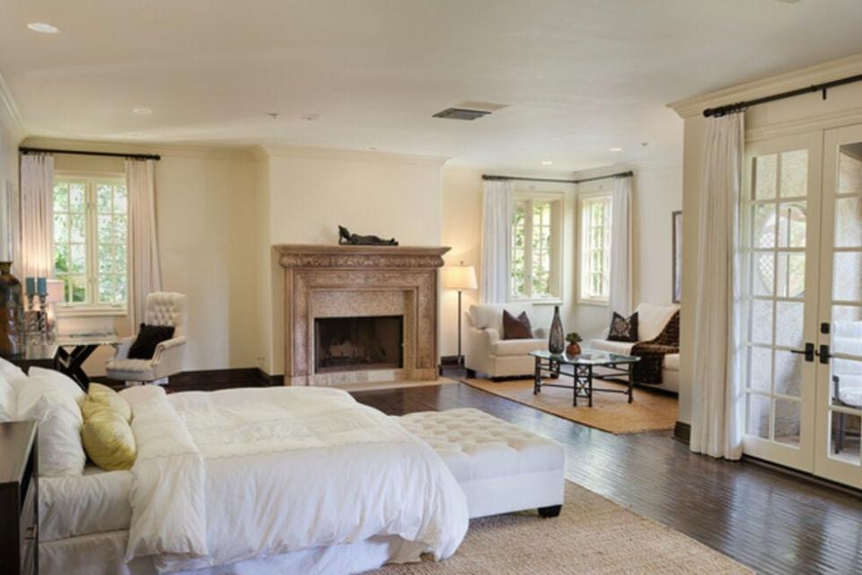 The master bedroom at the Beverly Grove Place with a sitting area, balcony and fireplace.