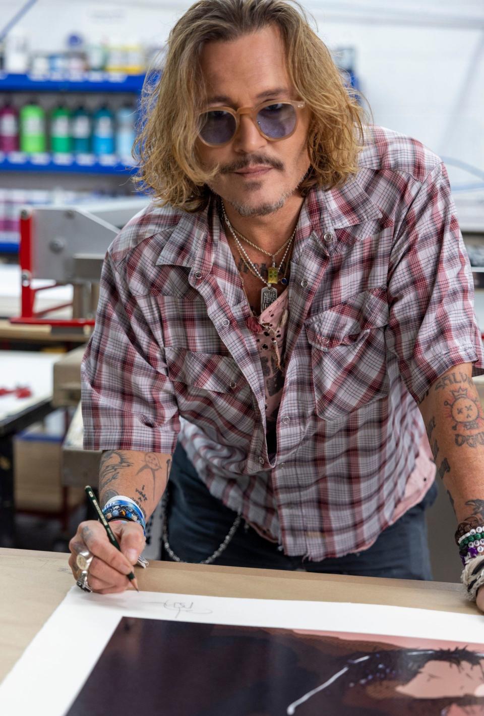 Johnny Depp signing a print of one of his artworks