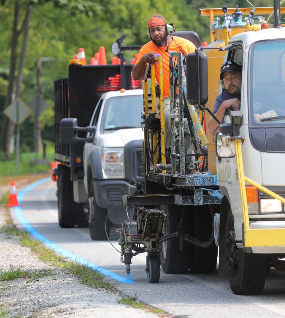 Rob Wyatt drives Atman Granberry as he sprays the blue line that will guide Akron Marathon runners along San Run Parkway on Monday, Sept. 13, 2021 in Akron, Ohio.  [Phil Masturzo/ Beacon Journal] 