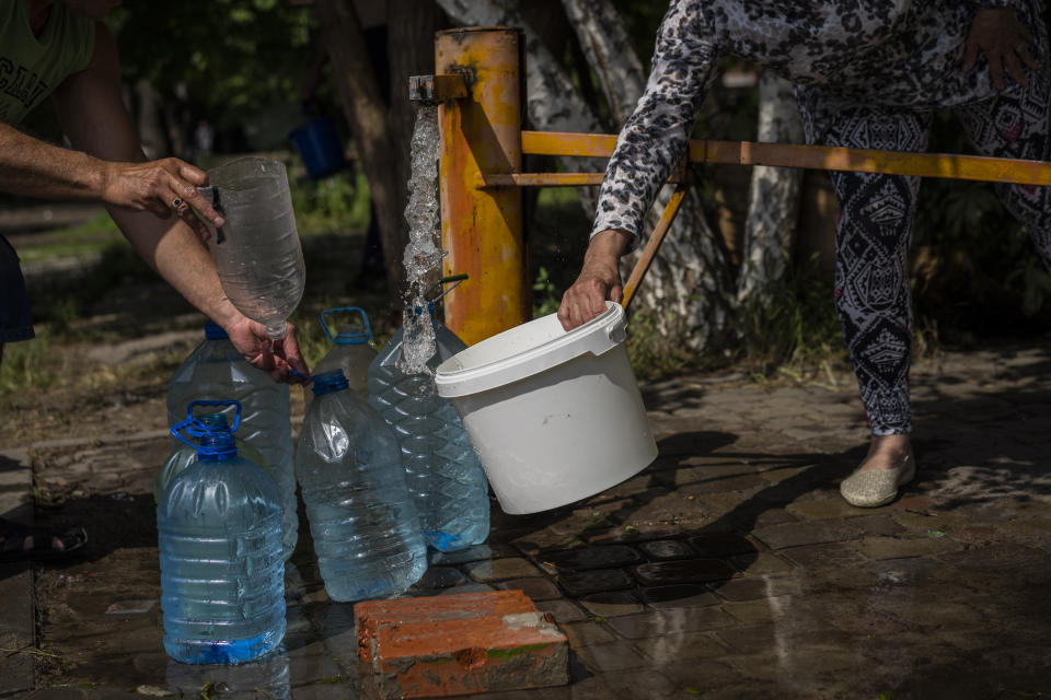 Residents collect water from a public pump in Slovyansk, eastern Ukraine, Saturday, June 4, 2022. (AP Photo/Bernat Armangue)