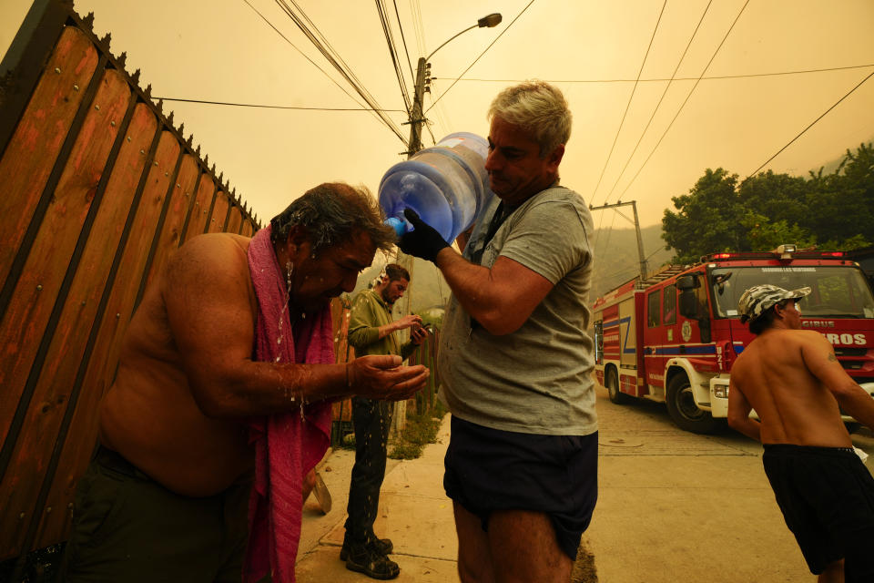 FILE - A man helps a fellow resident cool down with bottled water as wildfires burn nearby, in Vina del Mar, Chile, Saturday, Feb. 3, 2024. Scientists say climate change creates conditions that make the drought and wildfires now hitting South America more likely. (AP Photo/Esteban Felix)