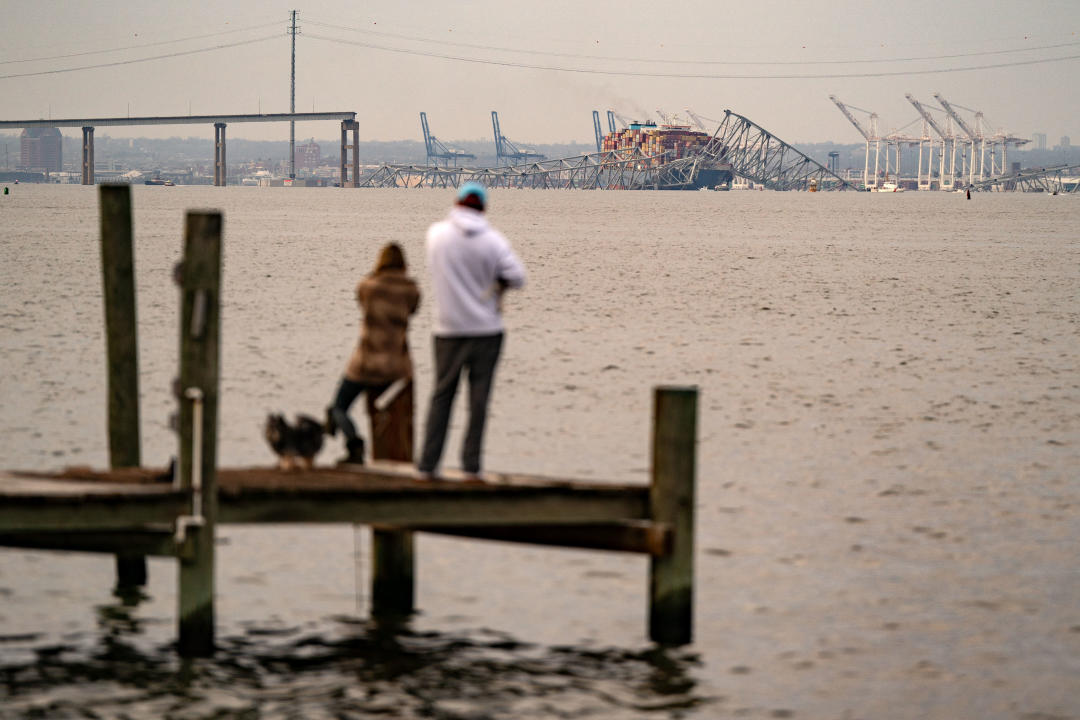 People look toward the Francis Scott Key Bridge following its collapse after the Singapore-flagged Dali container ship collided with it along the Patapsco River.