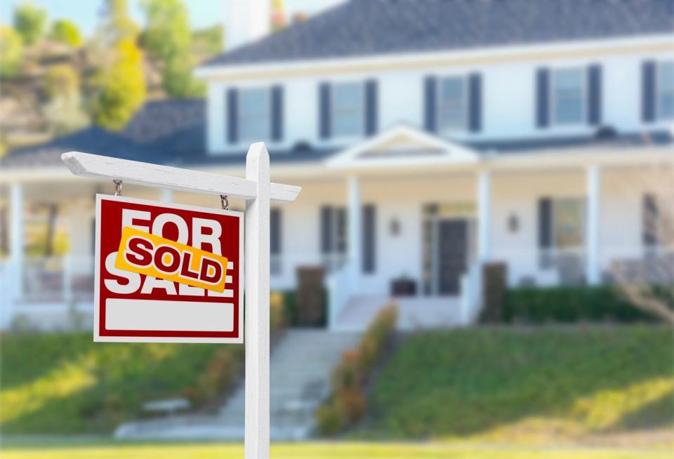 A suburban home with a For Sale sign in the front that has since been Sold.