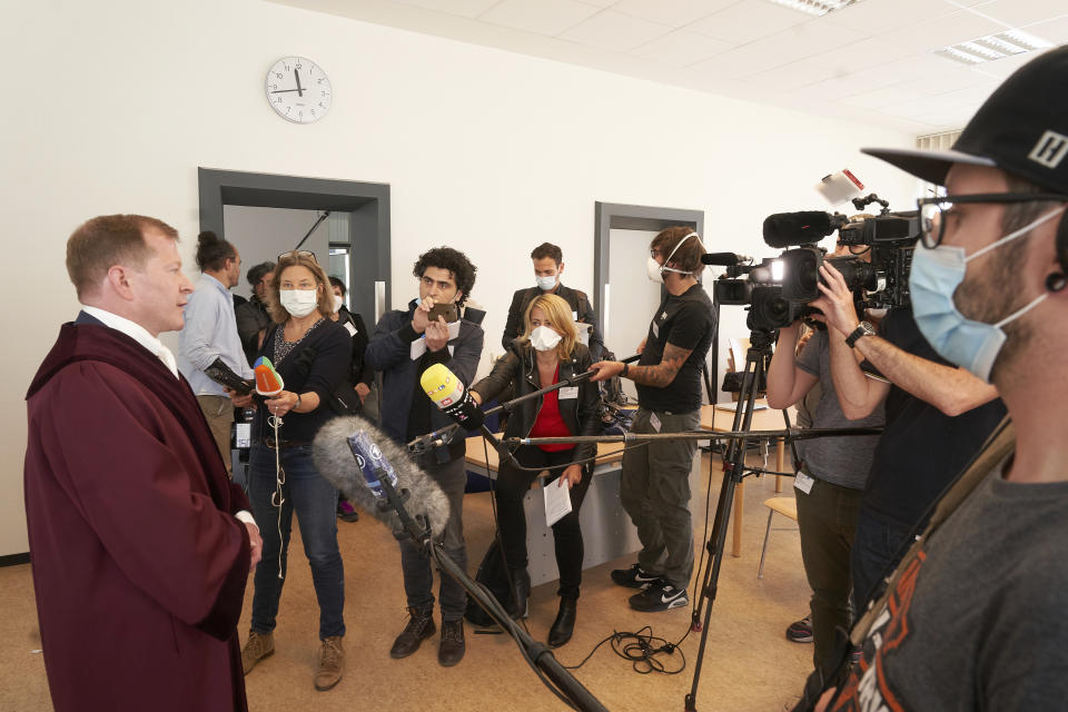 Senior public prosecutor Jasper Klinge, left, talks to journalists at the Koblenz court building after the end of today's trial in Koblenz, Germany, Thursday, April 23, 2020. Two former members of Syria's secret police go on trial Thursday in Germany accused of crimes against humanity for their role in a government-run detention center where large numbers of opposition protesters were tortured.(Thomas Frey/dpa via AP)