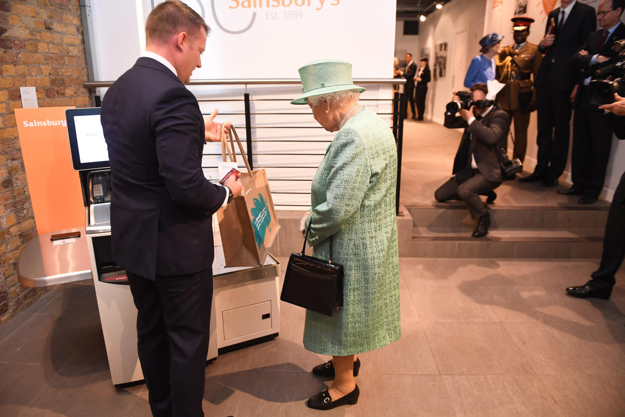 Queen Elizabeth II is shown a self-service checkout by Damien Corcoran, regional manager for Sainsbury’s stores 