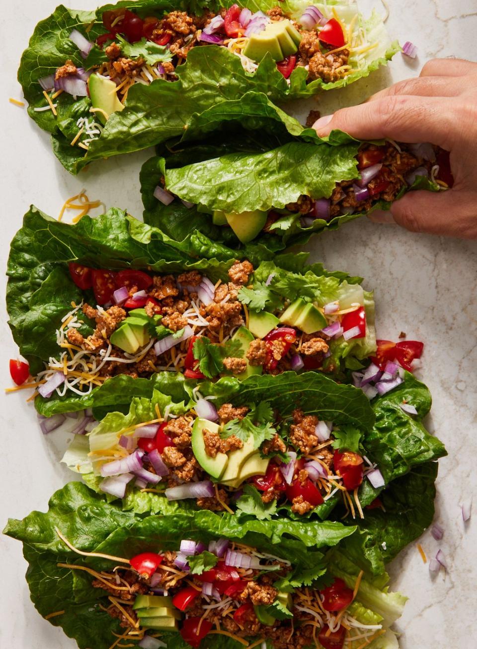 turkey taco lettuce wraps topped with cilantro, red onion, avocado, and tomatoes