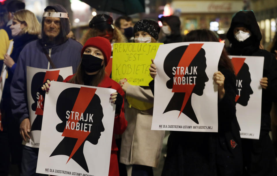 Protesters hold signs reading in Polish "women's strike" as they block a crossing in downtown Warsaw, Monday, Nov. 9, 2020, on the 12th straight day of anti-government protests that were triggered by the tightening of Poland's strict abortion law and are continuing despite a anti-COVID-19 ban on public gatherings. (AP Photo/Czarek Sokolowski)