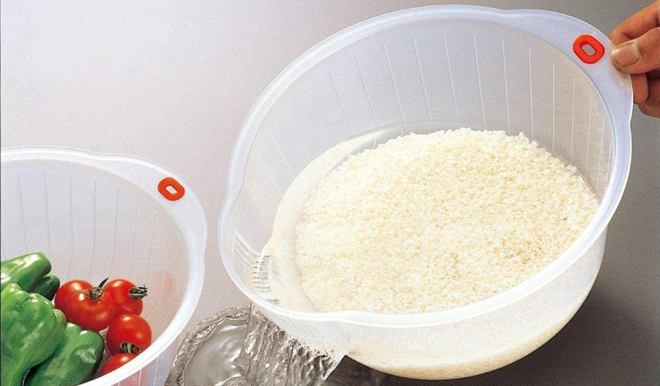 A rice strainer bowl with rice and water inside it