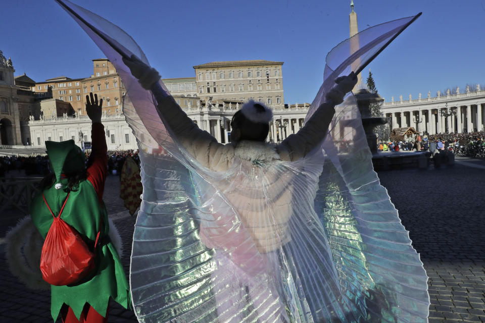 People in costumes salute Pope Francis as he recites the Angelus prayer from his studio's window overlooking St. Peter's square at the Vatican, Monday, Jan. 6, 2020. (AP Photo/Andrew Medichini)