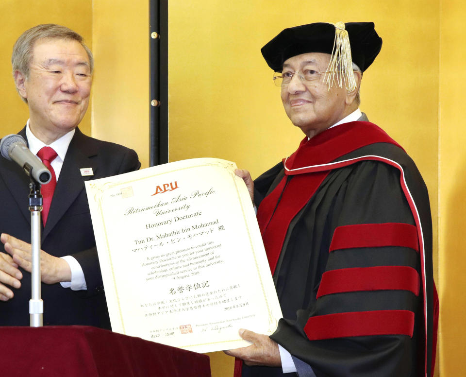 Malaysia's Prime Minister Mahathir Mohamad, right, receives honorary doctorate from Ritsumeikan Asia Pacific University at the university in Beppu, Oita prefecture, southern Japan, Thursday, Aug. 9, 2018. Mahathir called Thursday for more international exchange among young people as a way to prevent war and terrorism, as he received an honorary degree from the like-minded university in Japan. (Eri Shinagawa/Kyodo News via AP)
