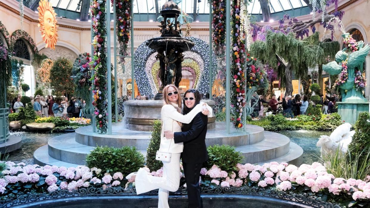 a bride in a white suit and a bride in a black suit pose at the bellagio in las vegas