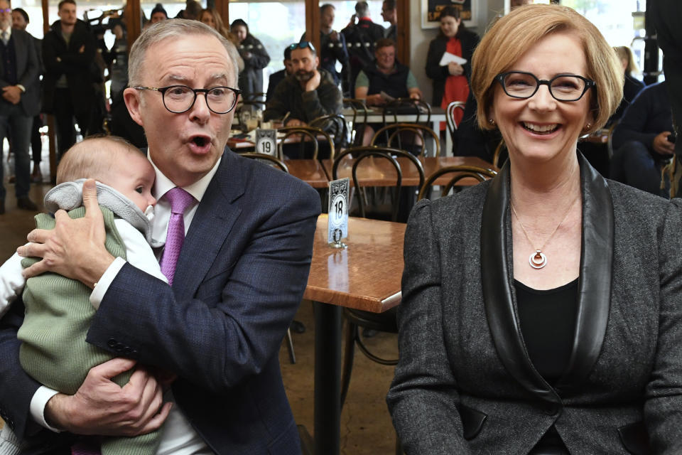 Leader of the center-left Australian Labor Party opposition Anthony Albanese, left, holds little baby Charlie as he shares a coffee with former Australian Prime Minister Julia Gillard while campaigning in Adelaide, Friday, May 20, 2022. The son of a single mother who raised him on a pension, Albanese had a humble start to life for a politician who could become Australia's prime minister on Saturday. (Lukas Coch/AAP Image via AP)