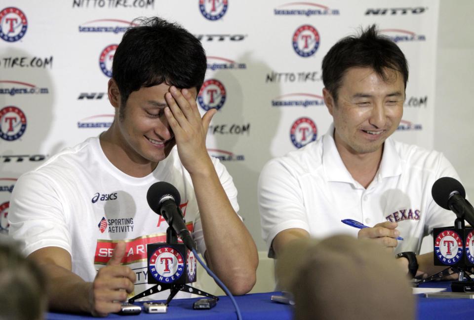 Texas Rangers' Yu Darvish wipes his forehead as he and his translator Kenji Nimura, right, smile after Darvish responded to a question about his first throwing session, at a news conference during baseball spring training Tuesday, Feb. 18, 2014, in Surprise, Ariz. (AP Photo/Tony Gutierrez)