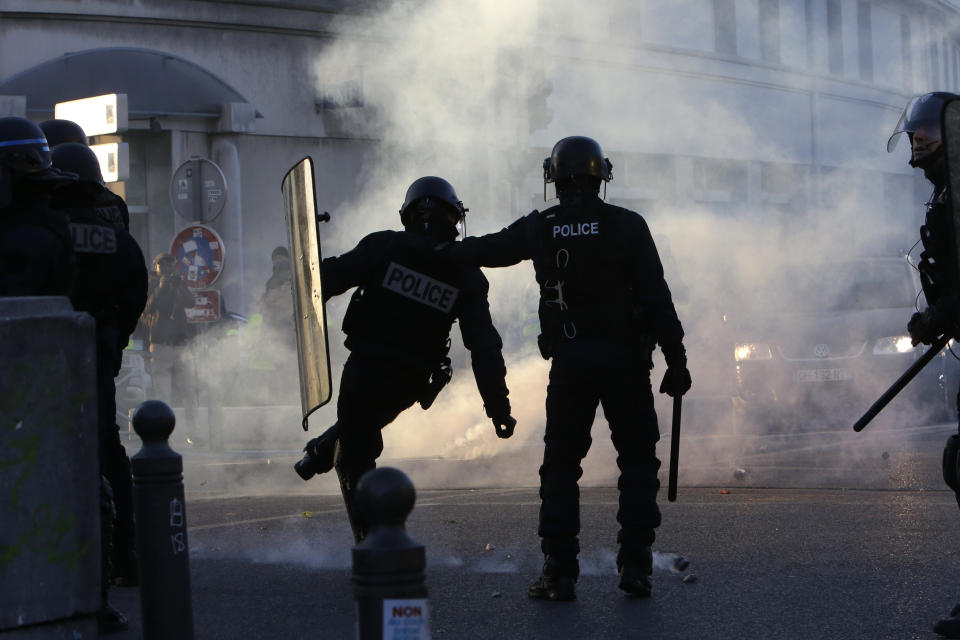 Riot police offiers kick back a tear gas grenade during a protest Saturday, Jan. 19, 2019 in Marseille, southern France. Thousands of yellow vest protesters rallied Saturday in several French cities for a 10th consecutive weekend, despite a national debate launched this week by President Emmanuel Macron aimed at assuaging their anger. (AP Photo/Claude Paris)