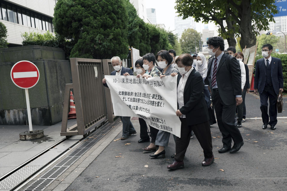 Plaintiffs and their supporters arrive at the Tokyo District Court Thursday, Oct. 14, 2021, in Tokyo. The court is hearing five ethnic Korean residents of Japan and a Japanese national demanding the North Korean government pay compensation over their human rights abuses in that country after joining a resettlement program there that promised a “paradise on Earth,” but without the presence of a defendant - the North’s leader. The banner on top reads: "Oct. 14 Tokyo District Court the North Korea "Paradise on Earth" campaign first trial. (AP Photo/Eugene Hoshiko)
