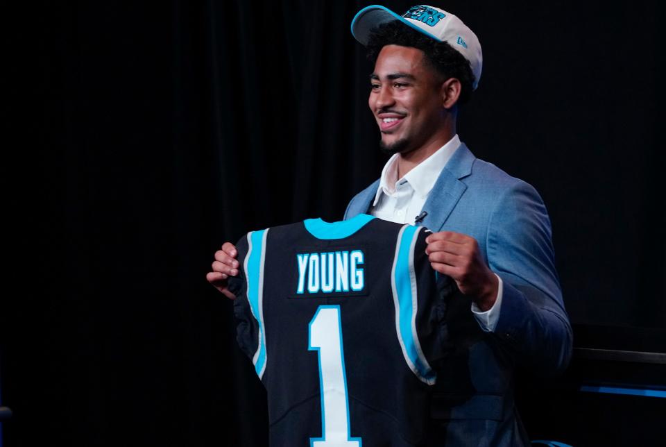 Carolina Panthers quarterback Bryce Young holds up a jersey depicting his draft position at Bank of America Stadium.