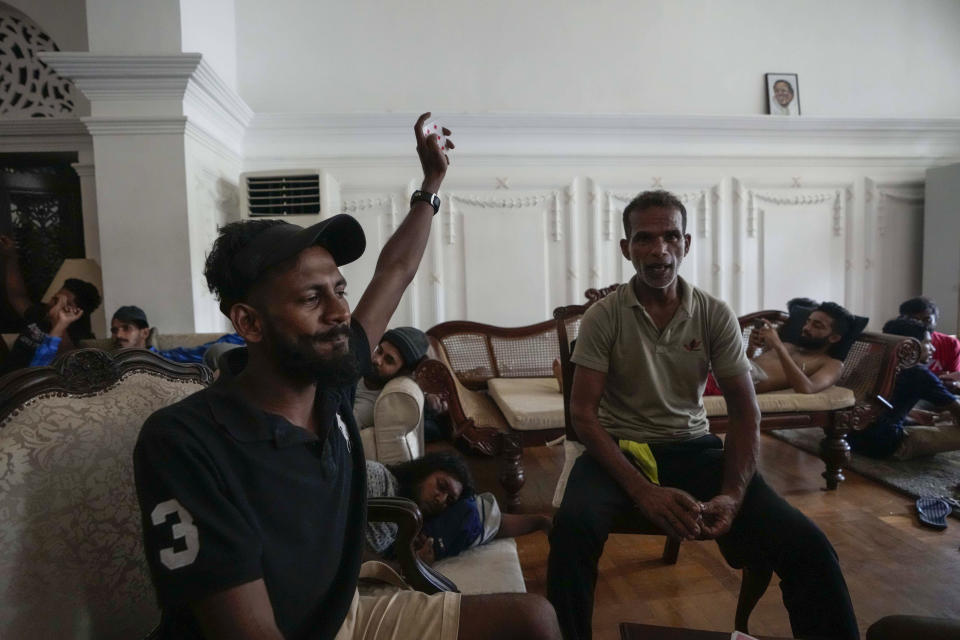 Protesters shout slogans as they stay and play cards in prime minister's official residence a day after it was stormed in Colombo, Sri Lanka, Sunday, July 10, 2022. Sri Lanka’s president and prime minister agreed to resign Saturday after the country’s most chaotic day in months of political turmoil, with protesters storming both officials’ homes and setting fire to one of the buildings in a rage over the nation's severe economic crisis.(AP Photo/Eranga Jayawardena)