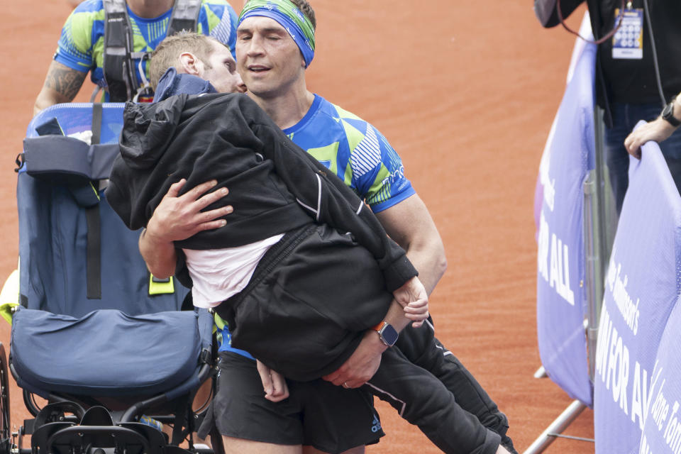 Kevin Sinfield carries Rob Burrow as he crosses the finish line of the '2023 Rob Burrow Leeds Marathon' which started and finished at Headingley Stadium, Leeds, May, 14, 2023. Rob Burrow, a former rugby star who was widely praised for his fundraising campaigns after being diagnosed with Lou Gehrig’s disease in 2019, has died. He was 41. (Danny Lawson/PA via AP)
