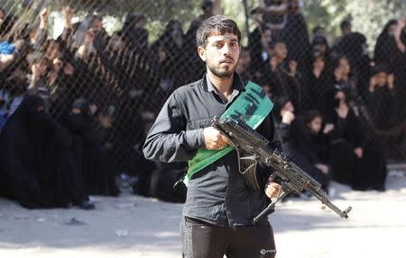 A Shi'ite fighter stands guard during a commemoration of Ashoura in Baghdad's Sadr City, November 4, 2014. REUTERS/Thaier Al-Sudani