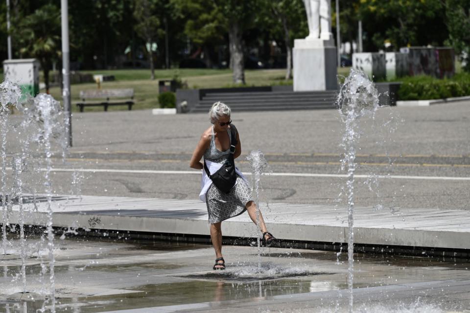 <span>A woman cools down in a water fountain during a heatwave in Thessaloniki on June 12, 2024. </span><div><span>SAKIS MITROLIDIS</span><span>AFP</span></div>