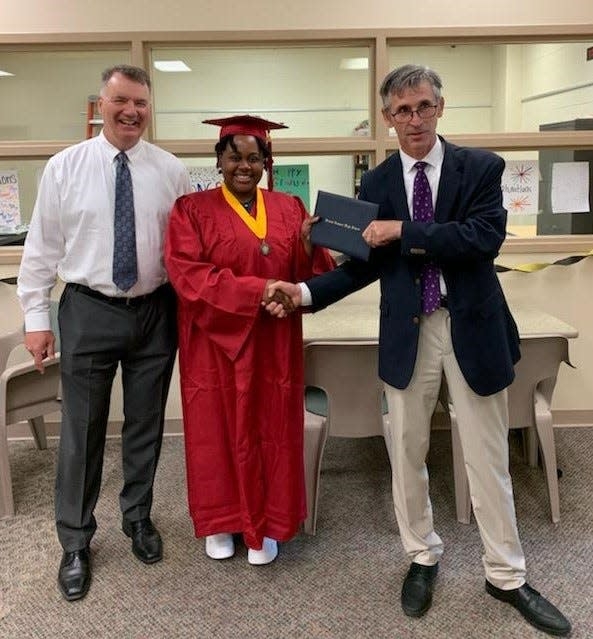 Pieper Lewis, center, earned her high school diploma on July 14. Her attorneys Paul White, left, and Matthew Sheeley, right, gave Lewis her diploma at the Polk County Juvenile Detention Center.