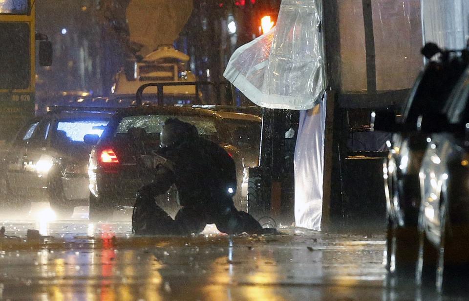 A member of the bomb squad inspects an object after a controlled detonation at the finish line of the Boston Marathon in Boston, Tuesday, April 15, 2014. Police have blown up two unattended backpacks found near the Boston Marathon's finish line on Tuesday. They say they've taken a man into custody in connection with them. (AP Photo/Michael Dwyer)