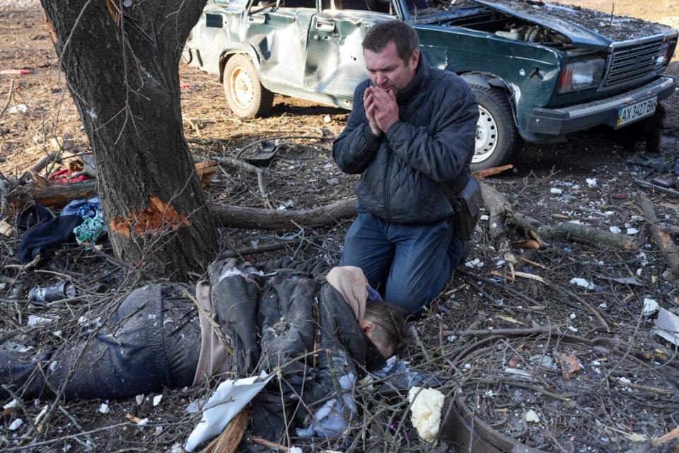 A man mourns near a body after an airstrike at an apartment complex