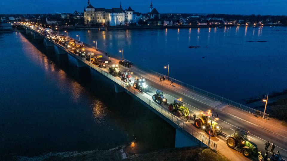 Tractors drive past Hartenfels Castle and cross the river Elbe in Torgau, eastern Germany. - Jens Schlueter/AFP/Getty Images