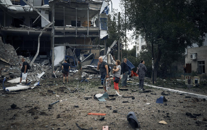 People stand in front of destroyed buildings after the Russian shelling in Mykolaiv, Ukraine, Wednesday, Aug. 3, 2022. According local media, supermarket, high-rise buildings and pharmacy were damaged. (AP Photo/Kostiantyn Liberov)
